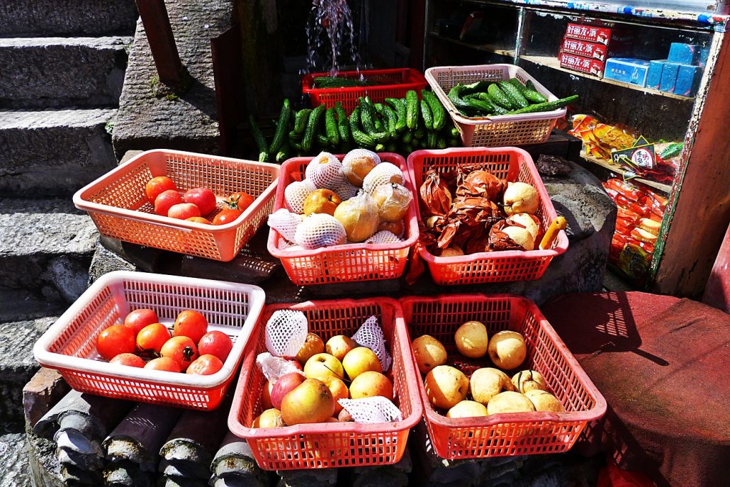 Red baskets of tomatoes, cucumbers, apples and pears at a mountain stall on Mount Hua.