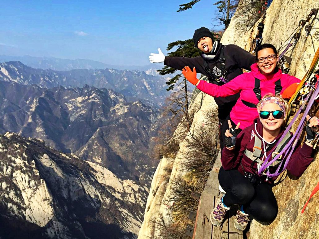 Alice and two friends grinning on the plank walk clipped to the cliff face on Mount Hua, China.