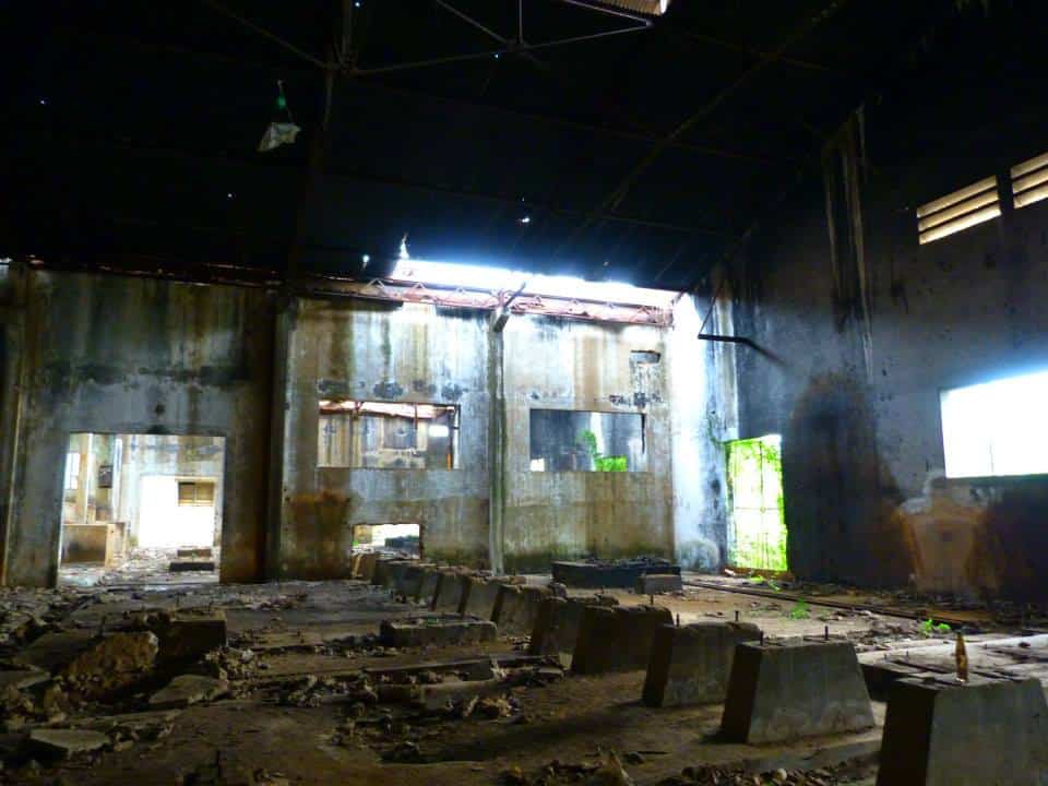 The gutted concrete interior of an abandoned building in Cambodia, rubble on the floor.