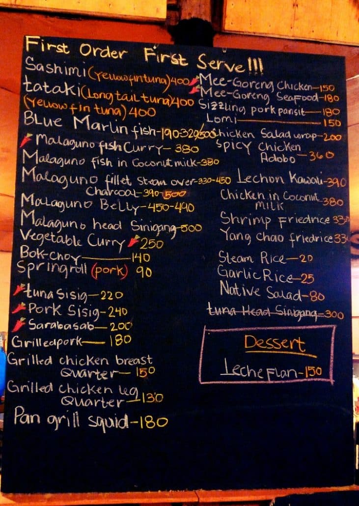 Chalkboard food menu at Sinugba sa Balay in Coron listing sashimi, fish curry and sisig dishes with prices