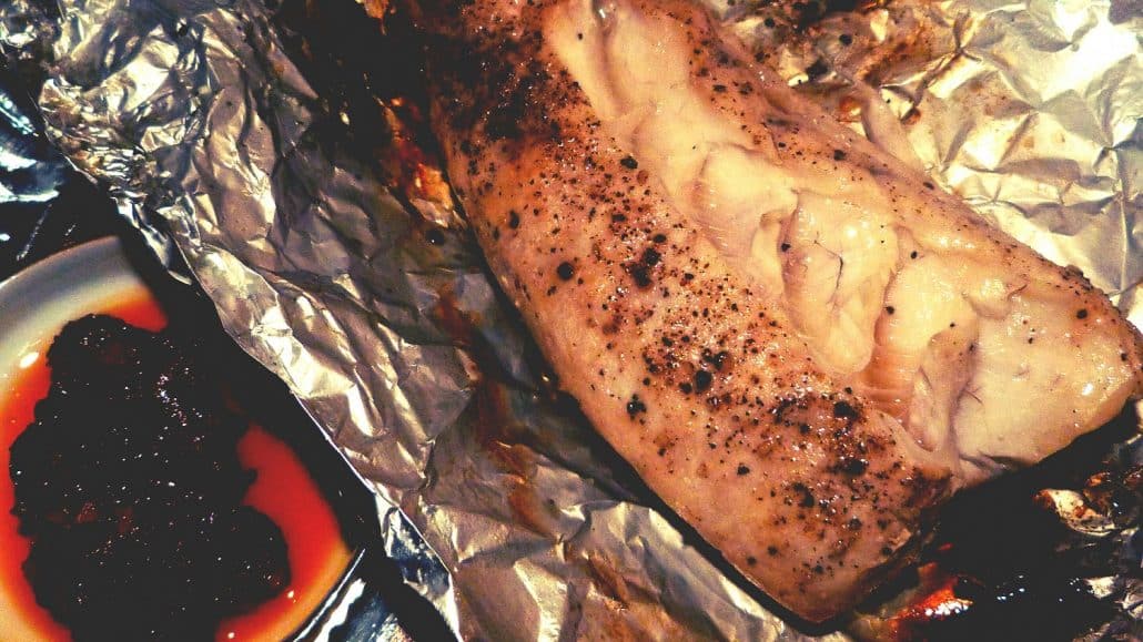 Grilled fish fillet on foil beside a small dish of dark dipping sauce in Coron