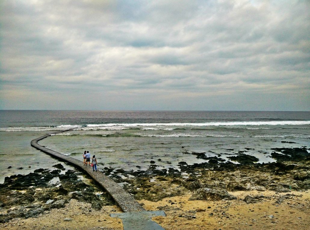 Concrete walkway leading out over the reef toward the sea under a cloudy sky at Green Island, Taiwan