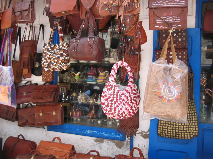 Leather and crocheted handbags hanging on display outside a Moroccan shop.