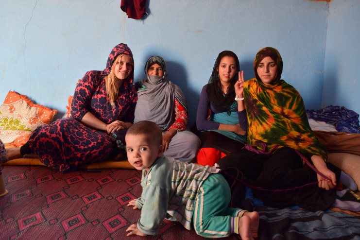 Alice sitting with four Moroccan women and a small child in a blue-walled room.
