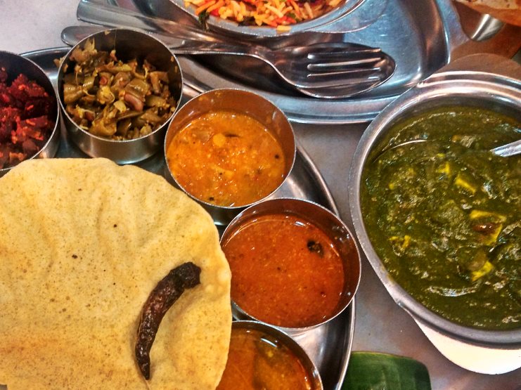 South Indian thali with papadum, spinach curry and small bowls of dal and sauces.