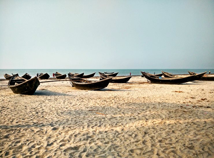 Wooden fishing boats resting on the wide sandy beach at Kuakata, Bangladesh.