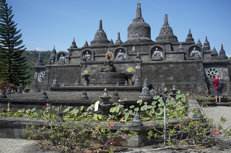 Stone Buddhist temple with stupas and seated Buddha statues at Brahma Vihara Arama, Bali.