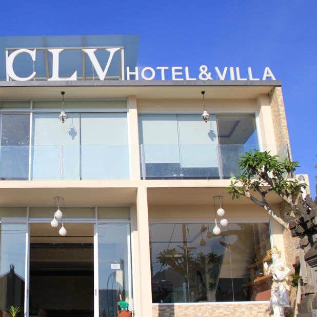 Facade of the modern glass-fronted CLV Hotel and Villa in Bali under a clear blue sky.