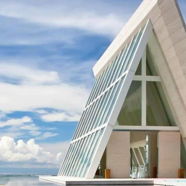 Triangular glass wedding chapel with a cross beside the sea at Conrad Bali.