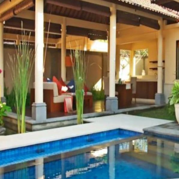 Open-sided villa lounge with a private pool and tall grasses at Kamuela Villas and Suites, Sanur, Bali.