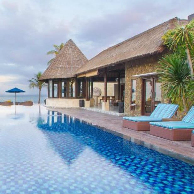Infinity pool beside a stone thatched building overlooking the sea at Lembongan Beach Club, Bali.