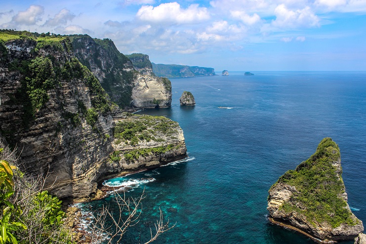 Rugged limestone cliffs and rock stacks meeting turquoise sea along the Nusa Penida coast, Bali.