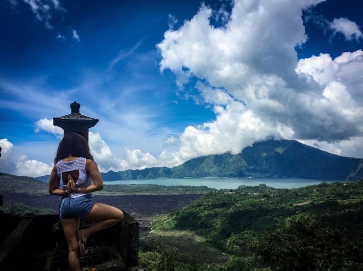 Alice practising yoga on a ledge overlooking Mount Batur and its lake in Bali.