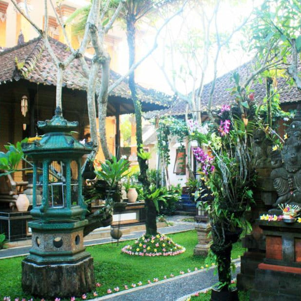 Balinese garden courtyard with a stone lantern, orchids and traditional buildings at Teba House, Ubud.