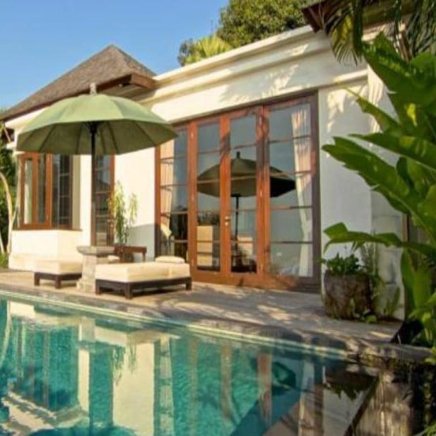 Private pool villa with a green parasol and sun loungers at The Damai in Lovina, Bali.