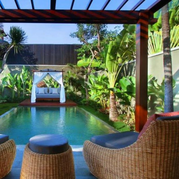 Private pool with a canopied daybed and wicker chairs on a covered terrace at The Ulin Villas and Spa, Bali.