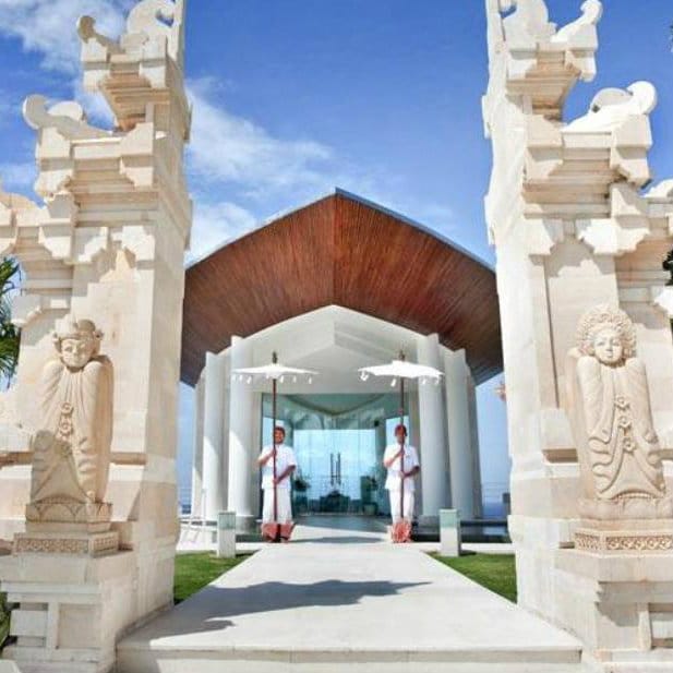 White Balinese stone gates framing an ocean-facing chapel at Grand Nikko, Bali.