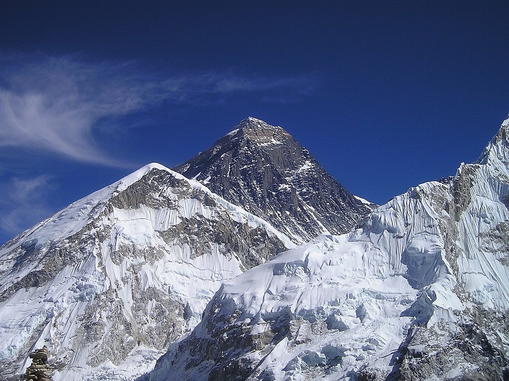 The dark rocky summit of Mount Everest rising above glaciers under a deep blue sky.