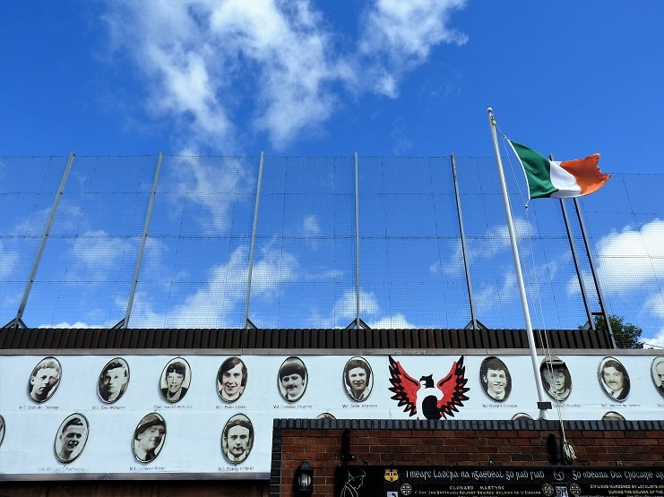 Portraits of fallen men and an Irish tricolour above a memorial wall in Belfast.