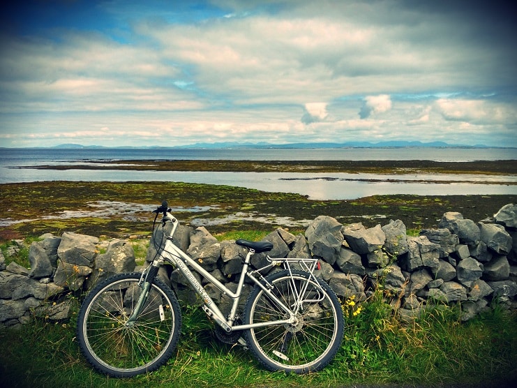 A silver bicycle leans against a dry stone wall overlooking the sea on the Aran Islands, Ireland.