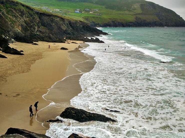 A sandy beach and turquoise surf backed by green headlands on the Dingle Peninsula, Ireland.