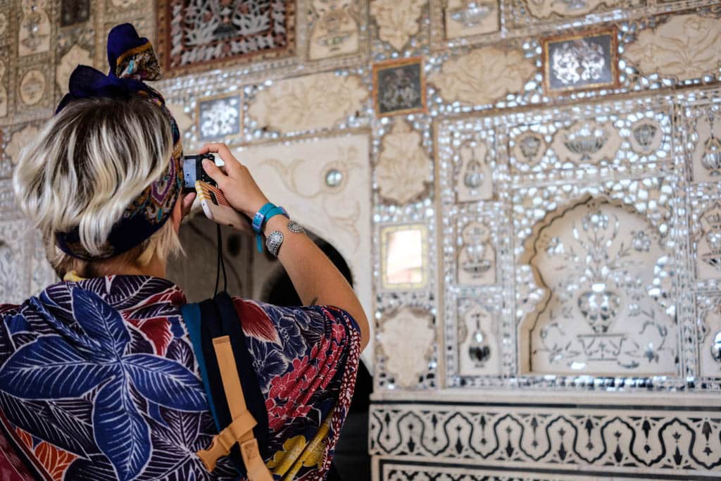 Alice photographs the mirrored mosaic walls of the Sheesh Mahal in Amber Fort, India.