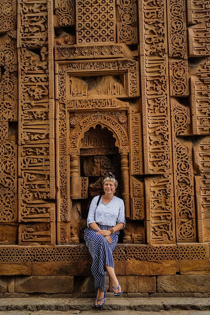 Alice sits against the carved sandstone walls of the Qutub Minar complex in Delhi.