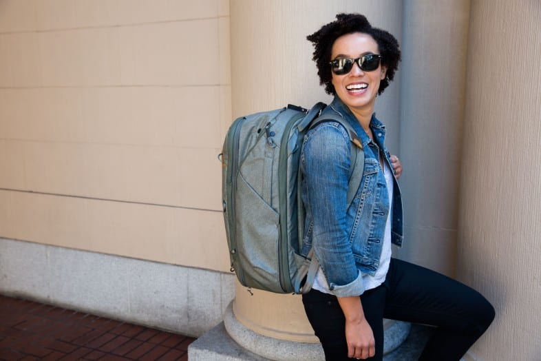 Woman carrying a teal green Peak Design 45L Travel Backpack