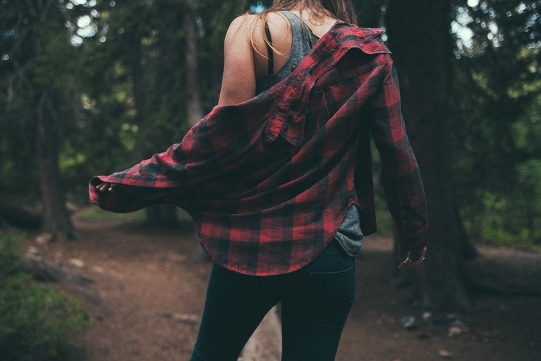 Woman running wearing a red and black chequered shirt in the wilderness