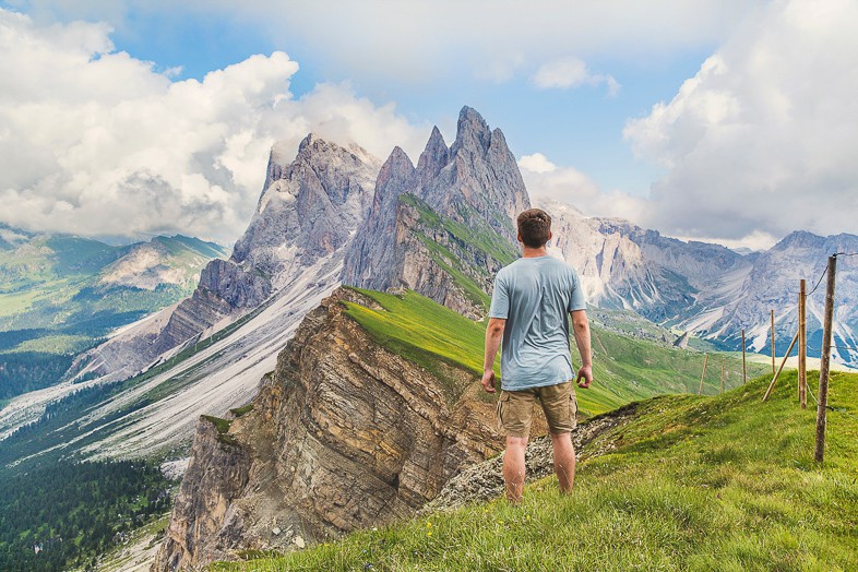 Solo traveler hiking on a sunny day and looking out on to jagged mountains