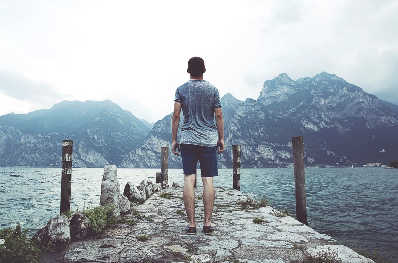 Man standing on a walkway on a lake leading to the edge