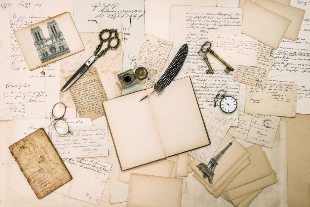 Layout of scissors, pens and old papers and cards ready to be put into a travel scrapbook for documenting travel memories