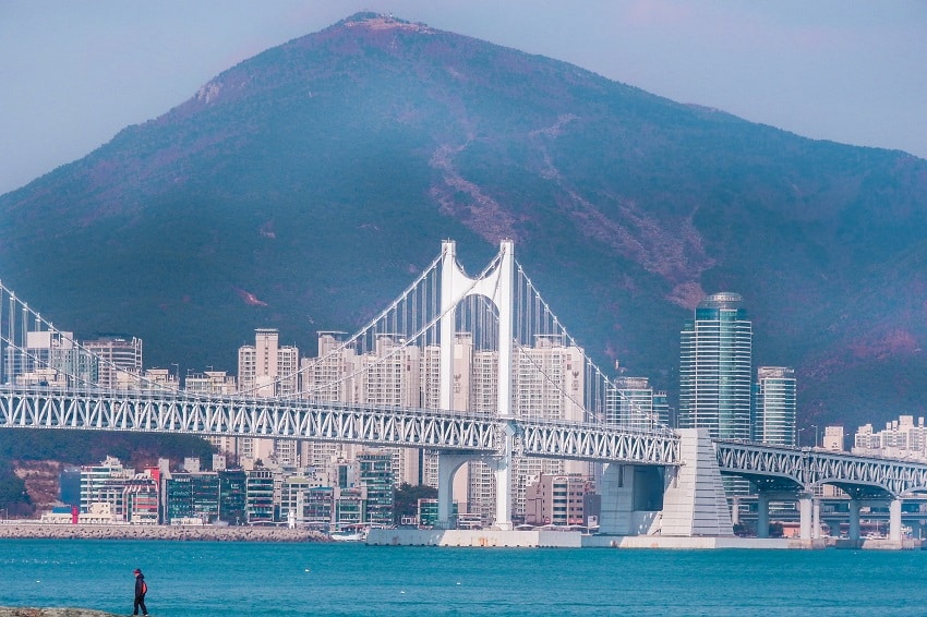 View of Gwangan Bridge from the coast of Busan with mountains in the background