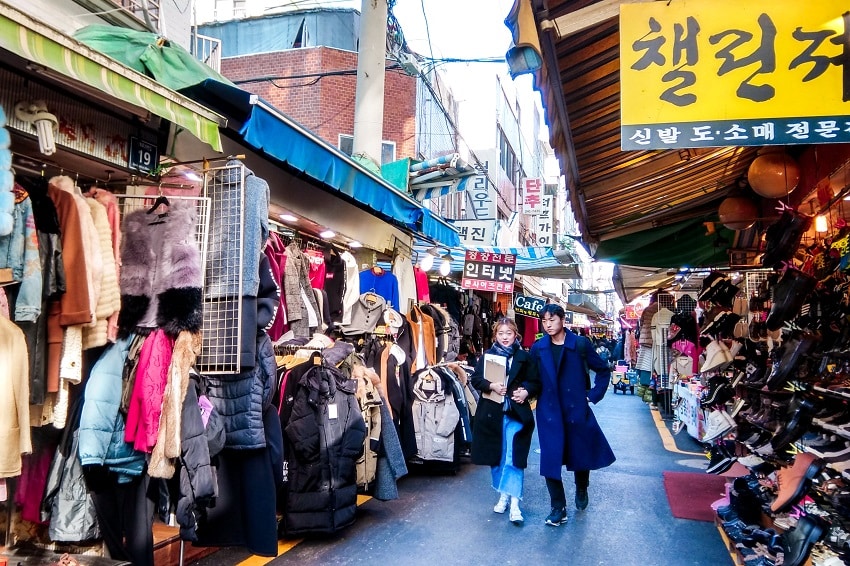 A couple shopping amongst rows of jackets in Nampodong's secondhand clothes market area